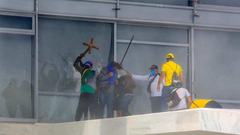 Supporters of Brazilian former President Jair Bolsonaro break a window as they invade Planalto Presidential Palace in Brasilia (Image: AFP via Getty Images)