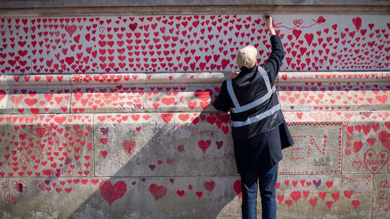 A volunteer adds hearts to the National Covid Memorial Wall in Westminster, central London (Image: PA)