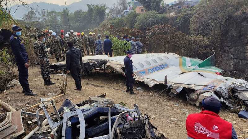 Rescuers stand by the wreckage of the plane (Image: Anish Bhattarai/AP/REX/Shutterstock)