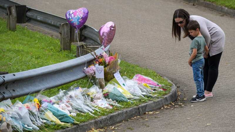 A woman and a boy look at floral tributes left at the scene in Plymouth on August 16, 2021 (Image: Getty Images)