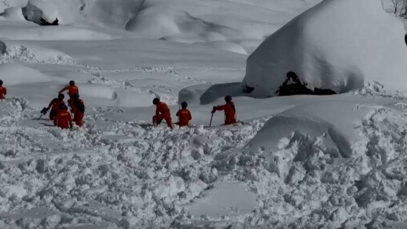 Members of a 1,000-person rescue operation trudge through the tundra in Tibet after an avalanche on Tuesday (Image: CCTV)
