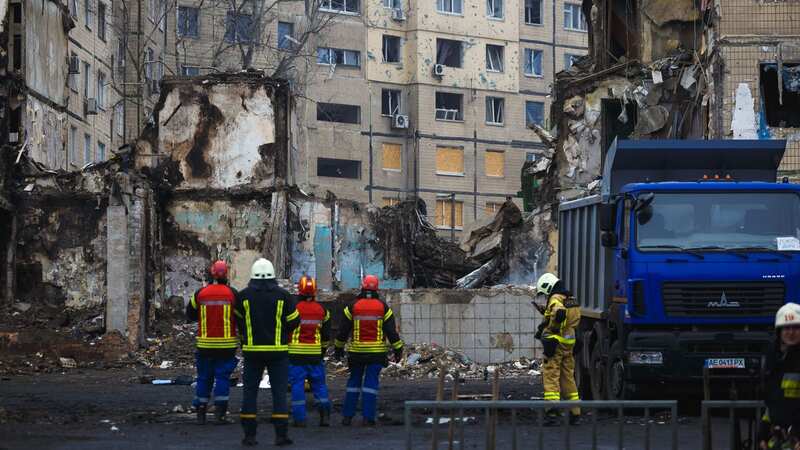 Rescuers stand near a high-rise building destroyed by a Russian missile (Image: Global Images Ukraine via Getty)