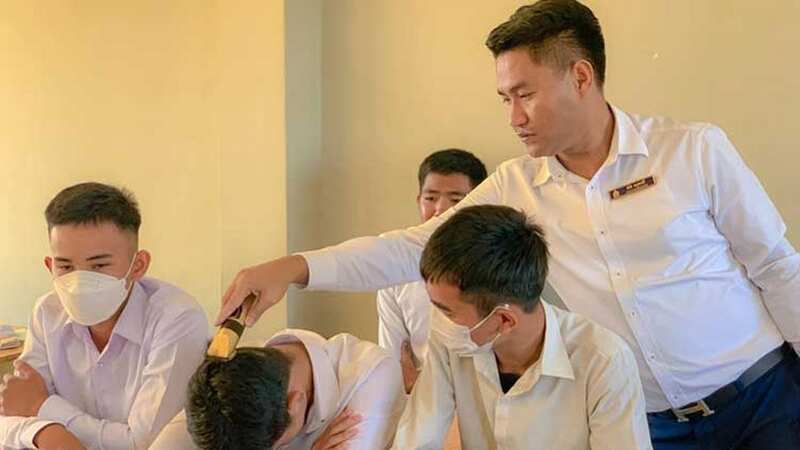 A teacher shaves a disconsolate lad in class as part of the harsh practice (Image: Facebook)