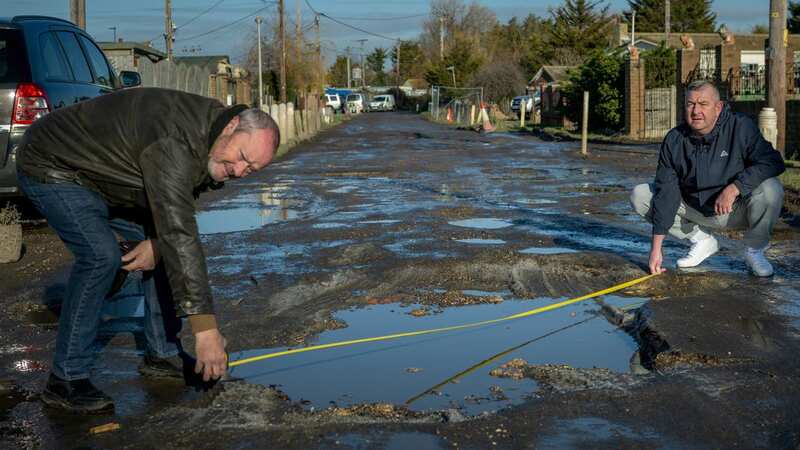 Paul Lucas and Aaron Dwyer measure one of the potholes on Seawick Road (Image: James Linsell-Clark/ SWNS)