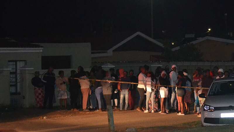 Bystanders wait behind a police tape marking the scene of a mass shooting in Gqeberha (Image: AFP via Getty Images)