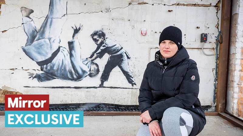 Yula Patoku poses with the Banksy artwork (Image: Rowan Griffiths / Daily Mirror)