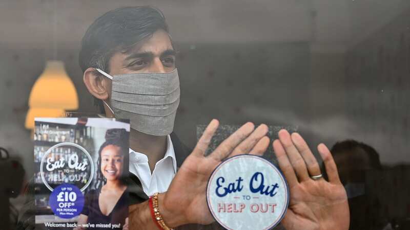 Rishi Sunak places an Eat Out to Help Out sticker in the window of a business (Image: PA)