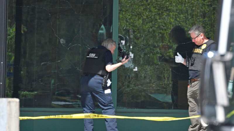 A technician photographs bullet holes in the front glass of the Old National Bank building in Louisville (Image: Timothy D Easley/AP/REX/Shutterstock)