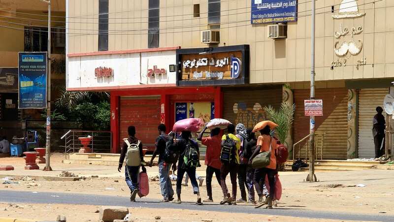People carrying their belongings walk along a street in Khartoum on April 16 (Image: AFP via Getty Images)