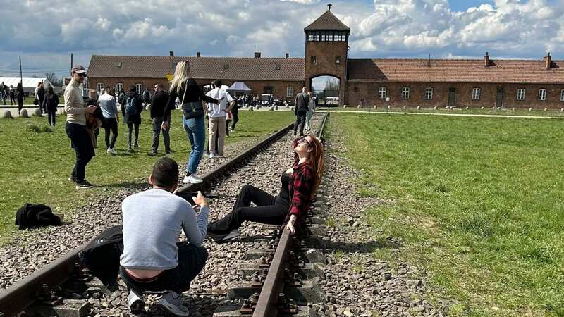 The woman was caught posing for the camera outside a former concentration camp in Poland (Image: Getty Images)