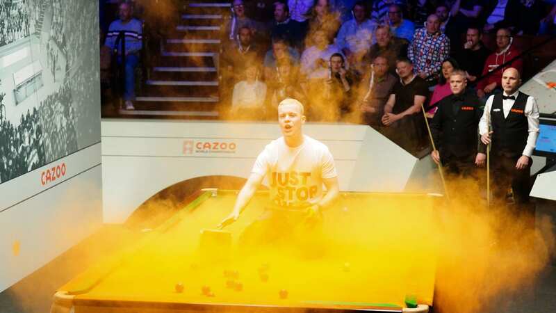 A Just Stop Oil protester jumps on the table during the World Snooker Championship match (Image: PA)