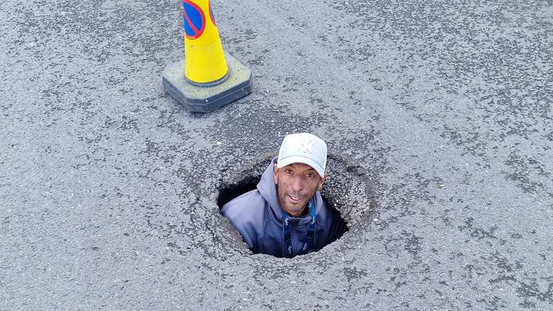Dean Hope, 41, pictured inside the pothole (Image: The Sun / News Licensing)