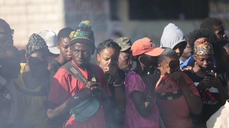 Bystanders watch the gang members burnt alive (Image: Odelyn Joseph/AP/REX/Shutterstock)