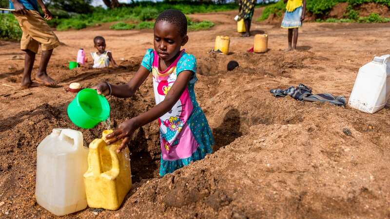 Children risk their lives digging holes in the river bed (Image: Adam Gerrard / Daily Mirror)