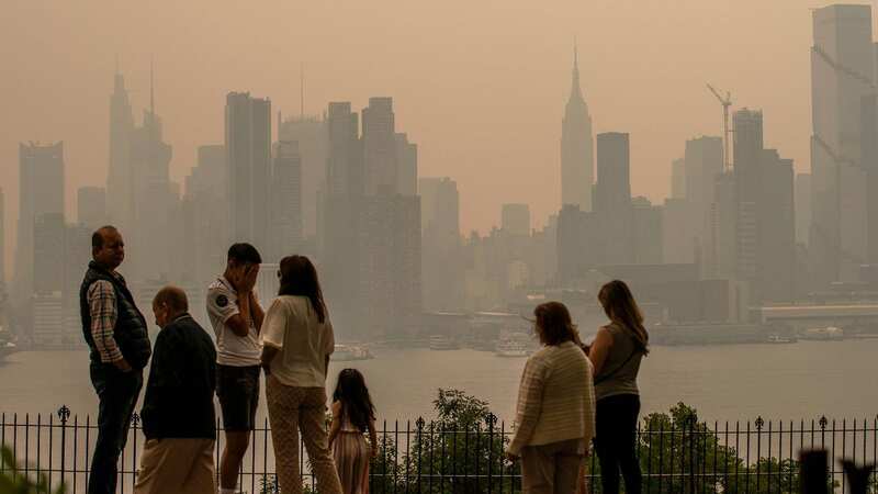 People stand in a park as the New York City skyline is covered with haze and smoke from Canada wildfires (Image: Getty Images)