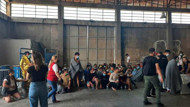 Survivors of a shipwreck sit in a warehouse, at the port in Kalamata town (Image: AP)