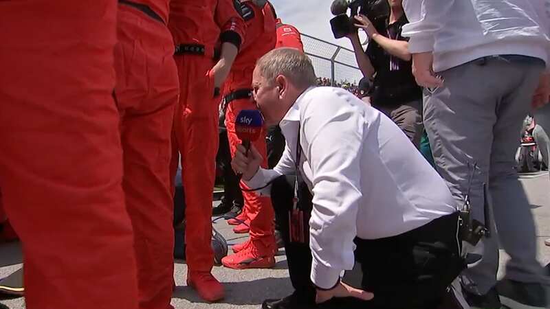 Martin Brundle crouched to look through Ferrari engineers