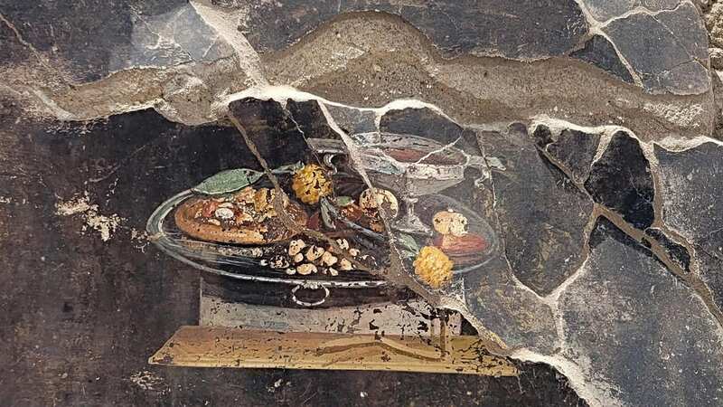 This ancient fresco includes what many think could be a very early form of pizza (pictured on the left of the plate) (Image: Parco Archeologico di Pompei pre)