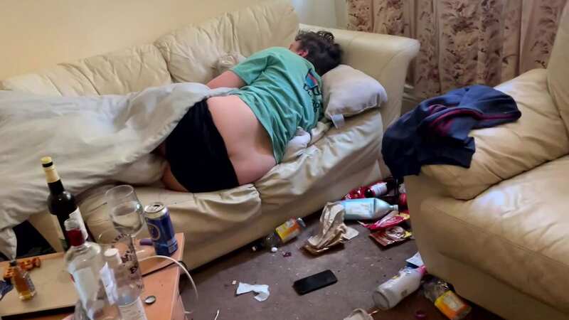 Woman viewing house finds man asleep on sofa surrounded by empty beer bottles