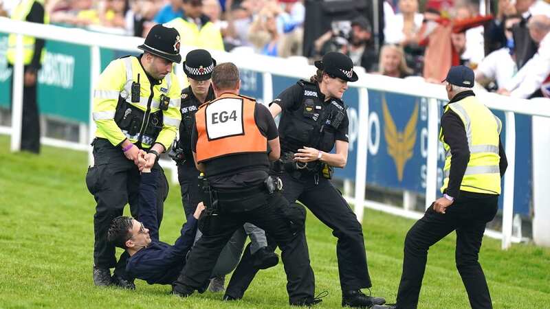 A protester is dragged off the track during the Epsom Derby (Image: PA)