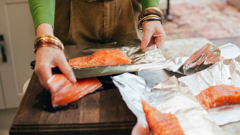 A woman is preparing to cook salmon in tin foil (Image: Getty Images)