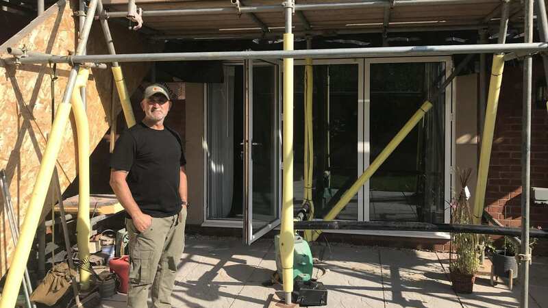 David Walker in front of his scaffolded house (Image: Swindon Advertiser / SWNS)