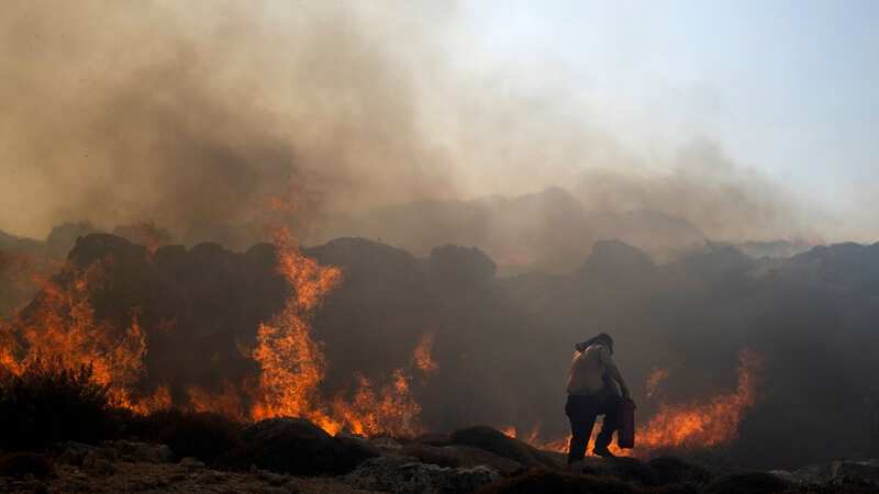 A man tries to extinguish a fire, near the seaside resort of Lindos, on the Aegean Sea island of Rhodes (Image: AP)