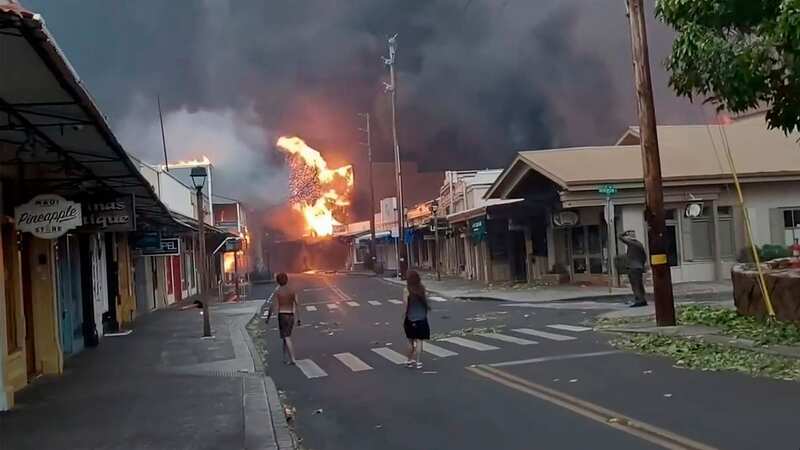 People watch as smoke and flames fill the air from raging wildfires on Front Street in downtown Lahaina (Image: AP)