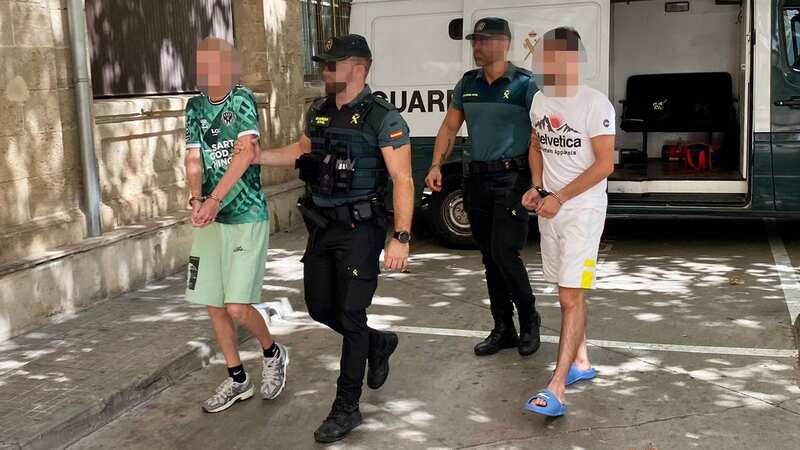 One of the arrested men is led inside by a Spanish police officer (Image: SOLARPIX.COM-G.Esteban)