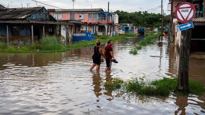 People wade through the water in a flooded area of Batabano, Mayabeque Province, Cuba, on August 28, 2023, as Tropical Storm Idalia approaches the western tip of the island nation (Image: AFP via Getty Images)