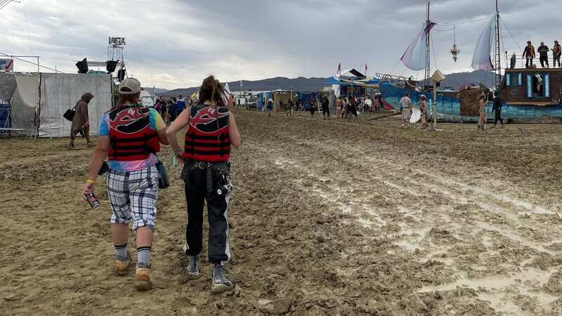 Attendees walk through a muddy desert plain (Image: AFP via Getty Images)