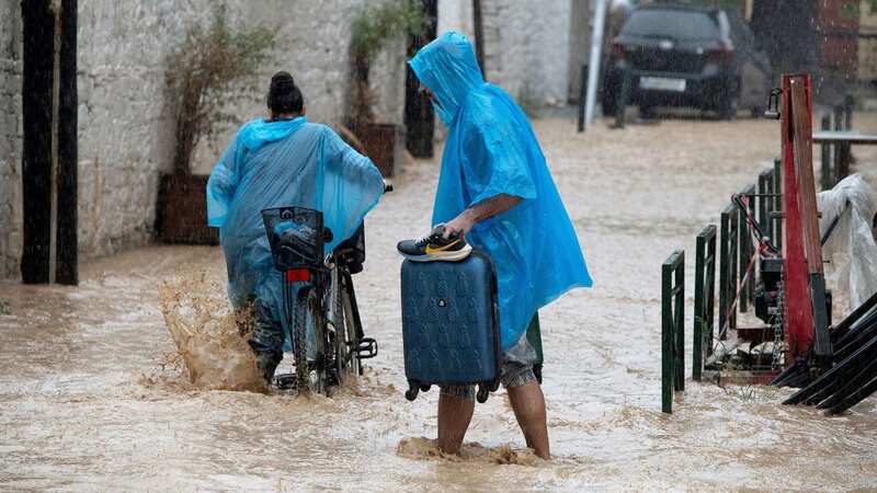 A man and a woman carry their belongings through a flooded road in Volos, Greece (Image: HATZIPOLITIS NICOLAOS/EPA-EFE/REX/Shutterstock)