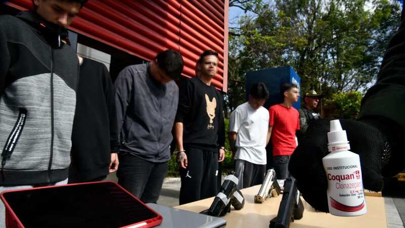 Colombian police parading a gang who used attractive women as bait to kidnap and rob their victims (Image: @PoliciaMedellin/X)