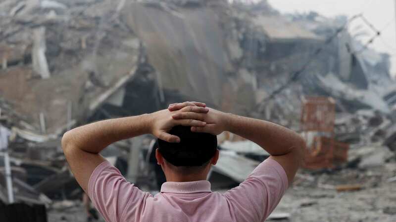 A Palestinian man stands in front of the rubble of Gaza City