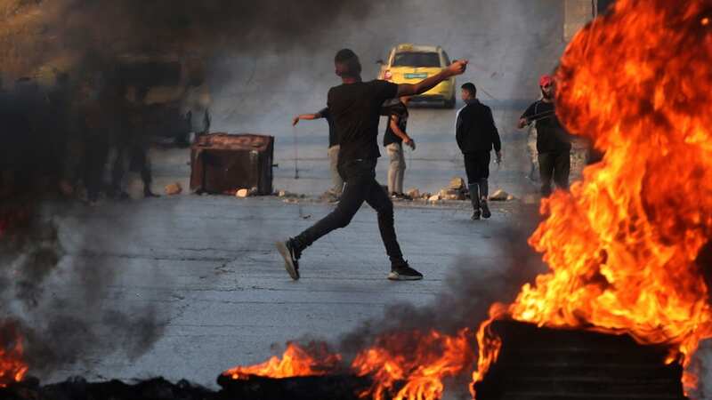 A Palestinian demonstrator throws rocks towards Israeli soldiers during clashes in the city of Ramallah in the occupied West Bank yesterday (Image: AFP via Getty Images)
