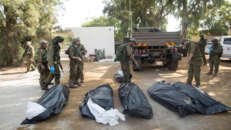 Israeli soldiers remove the bodies of civilians in Kfar Aza (Image: Getty Images)