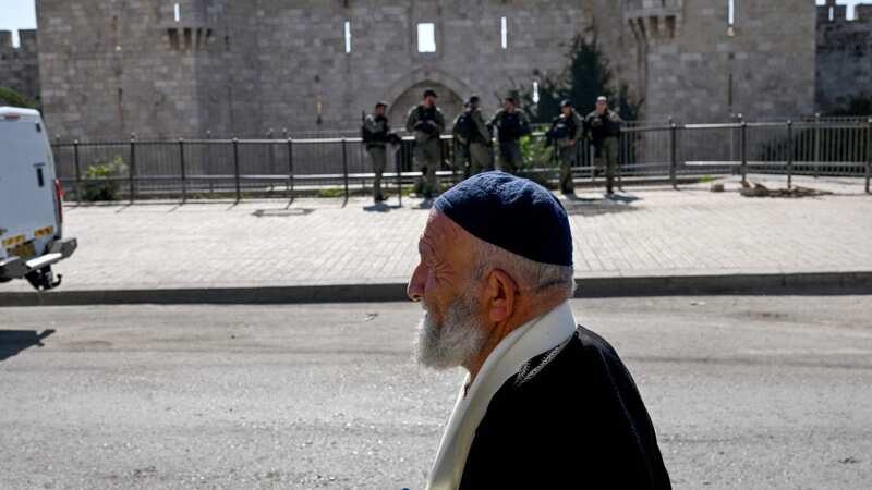 A Palestinian Muslim man walks past Israeli security forces stationed outside the Damascus Gate (Image: AFP via Getty Images)