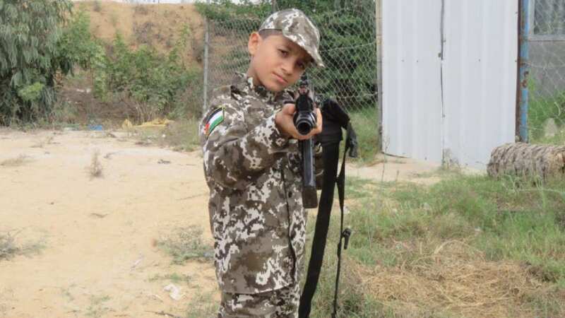 A young boy dressed in military uniform and pointing a gun, apparently trained by Hamas (Image: @southfirstresponders)