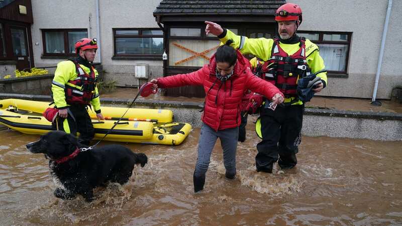 Members of the emergency services help a woman in Brechin, Scotland, as Storm Babet batters the country (Image: PA)
