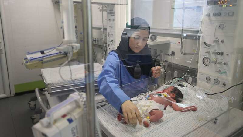 Nurse in Gaza with a tot who lost mum (Image: Anadolu via Getty Images)
