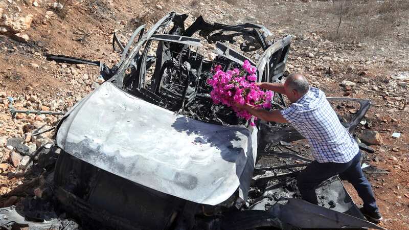 Samir Ayoub, uncle of three children who were killed by an Israeli airstrike, puts flowers on their car in the town of Ainata (Image: AP)