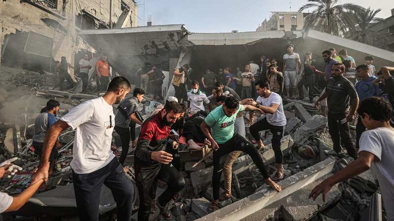 Civil defence teams and local people carry a person who was rescued alive under the rubble of the destroyed building belonging to Al Astal family (Image: Anadolu via Getty Images)