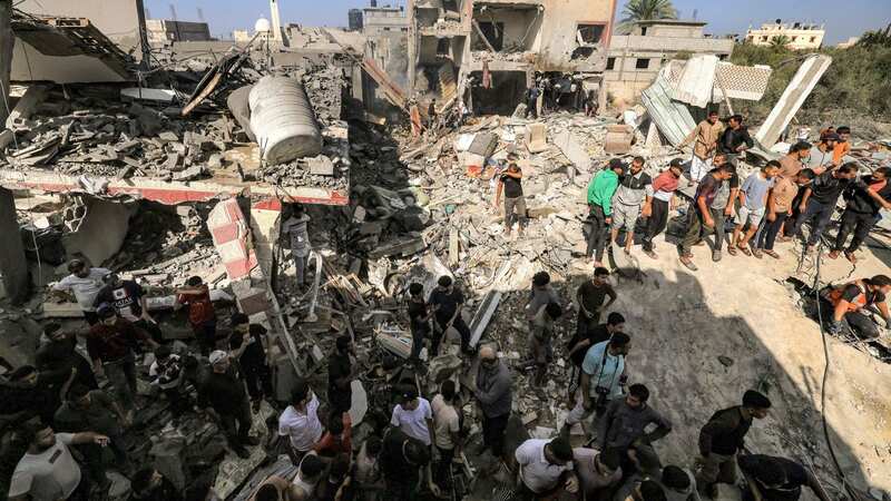 People gather by the rubble of a building that collapsed after Israeli bombardment while searching for survivors (Image: AFP via Getty Images)