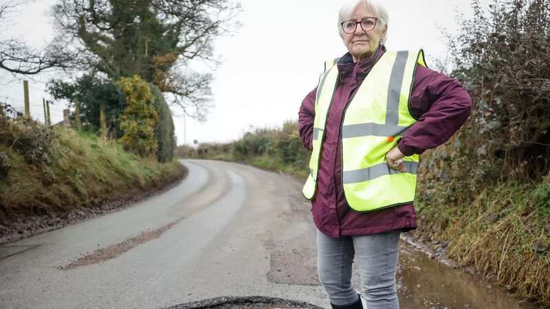 Sandra Hilton, 71, standing beside the cavernous pothole in Caverswall, Staffordshire (Image: Pete Stonier/Stoke Sentinel)