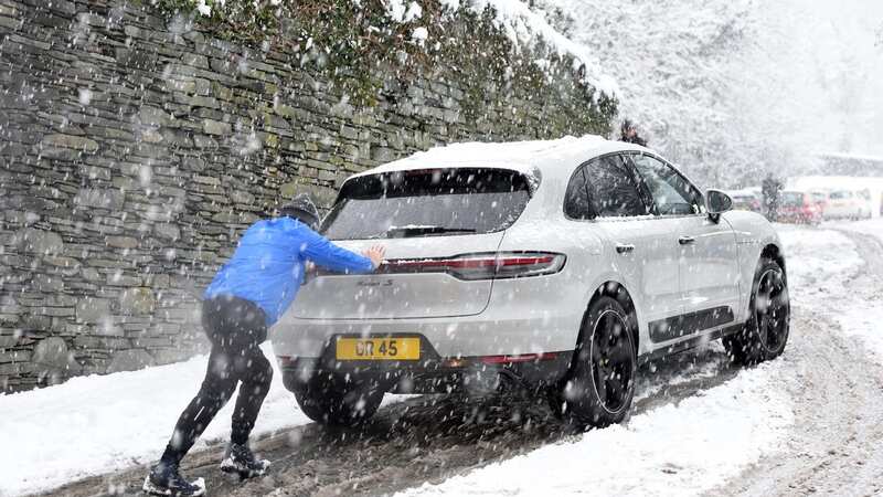 A man pushes a car the A591 in Windermere, Cumbria (Image: Asadour Guzelian)