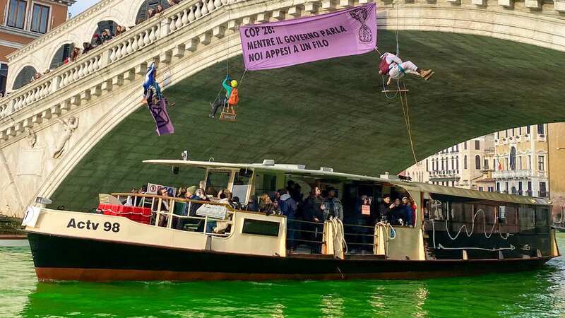 Members of Extinction Rebellion hang from the Rialto Bridge over the Grand Canal, which they had turned green with a non-toxic dye (Image: AP)