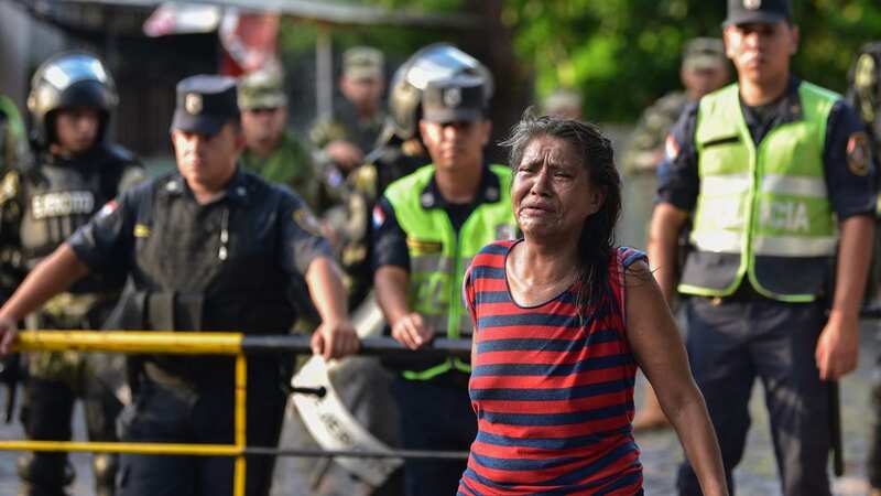 A relative of an inmate of the Tacumbu prison cries while policemen transport inmates to other prisons (Image: AFP via Getty Images)