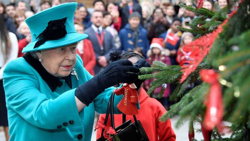 Queen Elizabeth II and Shylah Gordon, aged 8, attach a bauble to a Christmas tree in 2018 (Image: Getty Images)