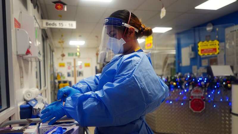 A nurse puts on PPE on a ward at King