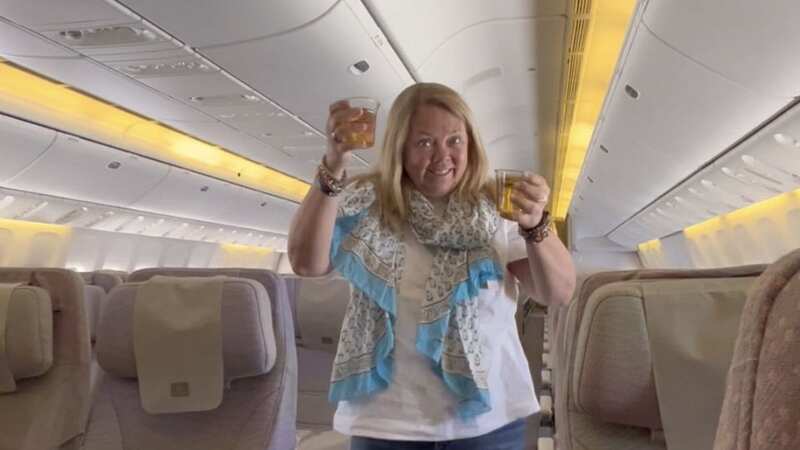 Kimmy Chedel, 59, walks down the aisle drinks in hand of the empty Emirates flight (Image: Zoe Doyle / SWNS)